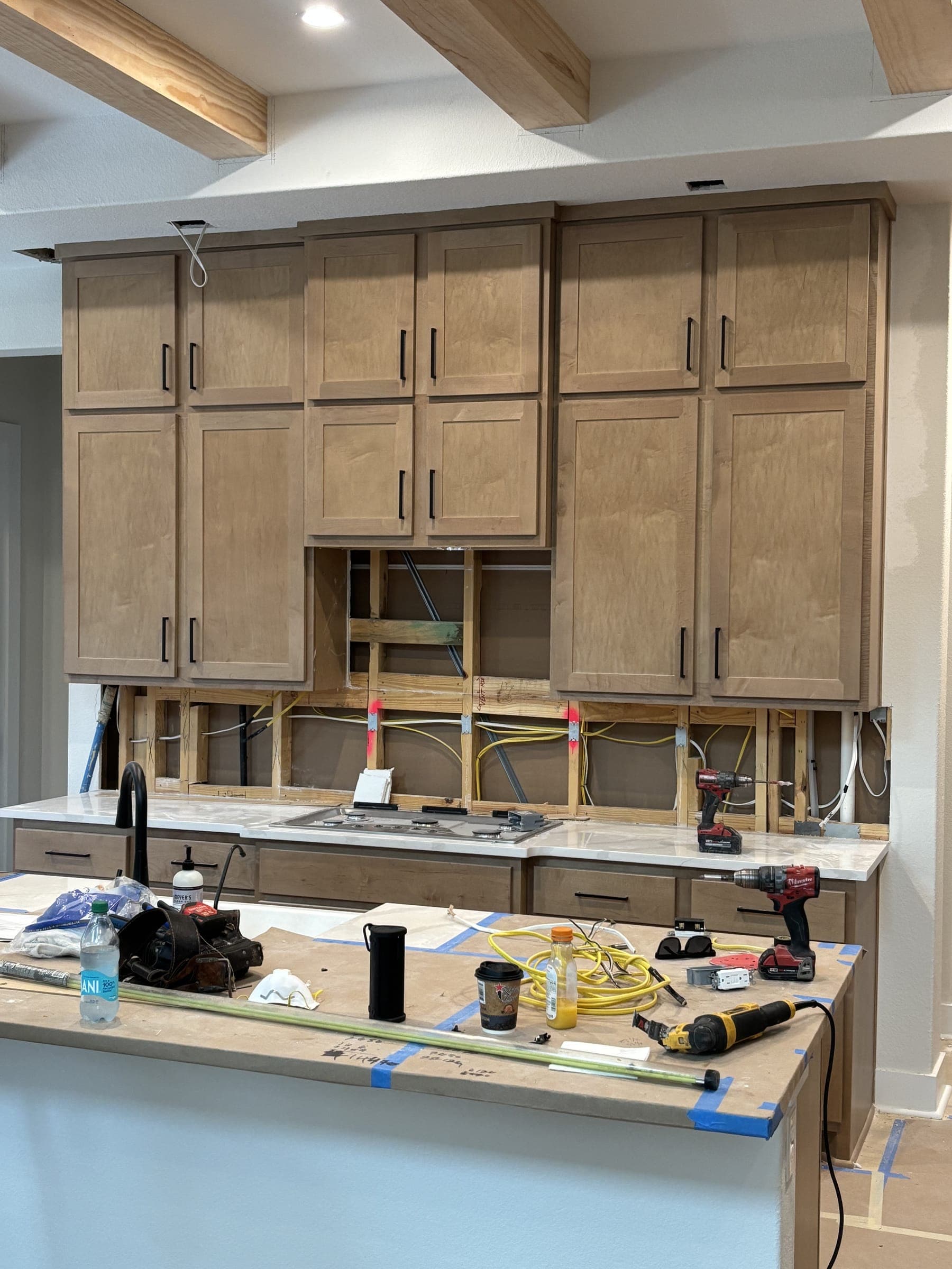 A kitchen mid-build, cabinets stripped back and tools still on the counter