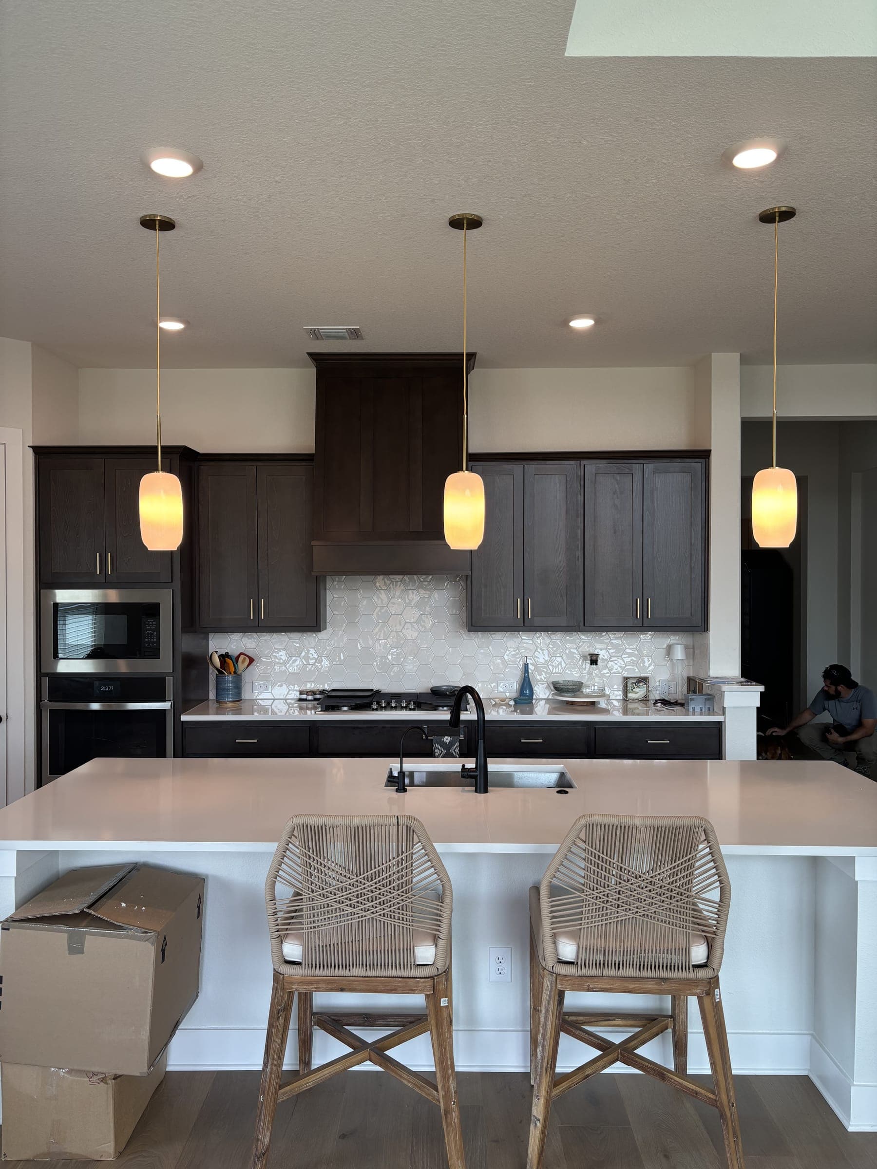 Kitchen island with woven counter stools and a tiled splashback
