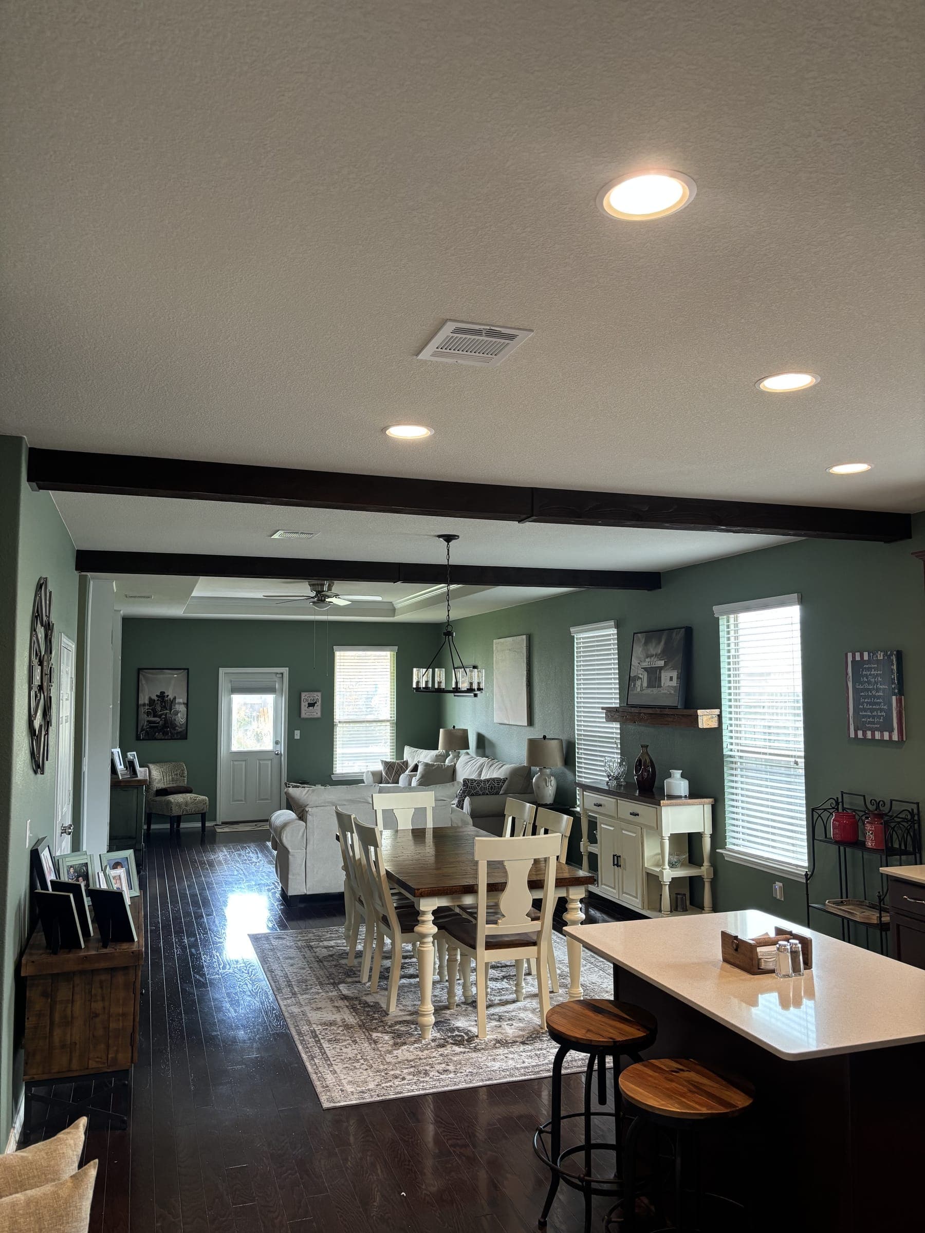 Open plan living and dining room with beams and sage green walls